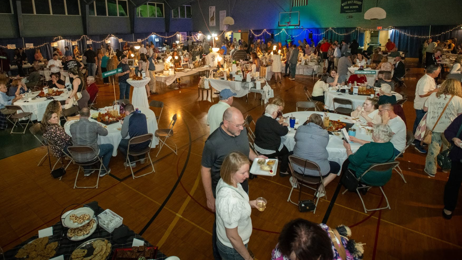 Group of people in the gymnasium enjoying food and drinks at a fundraiser
